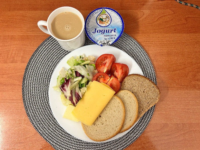 Na zdjęciu: Jogurt naturalny, Kawa zbożowa z mlekiem, Chleb mieszany pszenno-żytni, Chleb Graham, Masło extra 82%, Ser żółty, Pomidor, ​​​​​​​Mix sałat